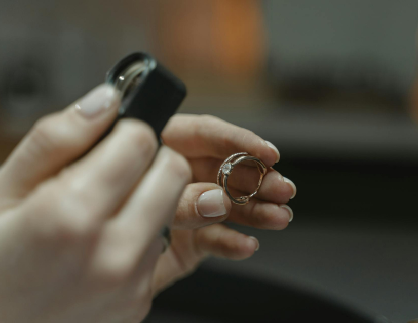A jeweler doing appraisals uses a loupe to examine a diamond ring.