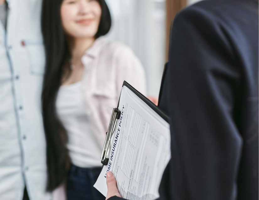 An insurance agent holds an insurance policy for a young couple after they had appraisals completed