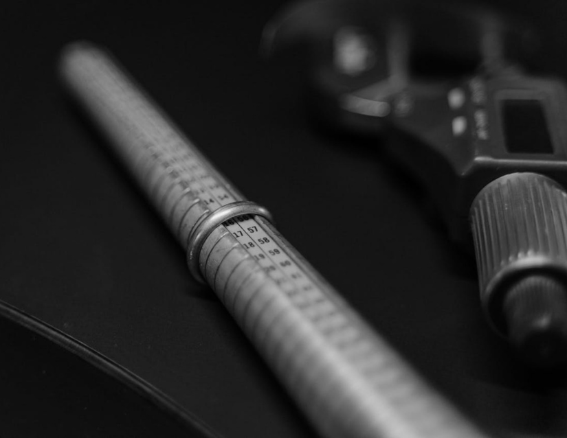 A white gold ring on a ring sizer next to a micrometer