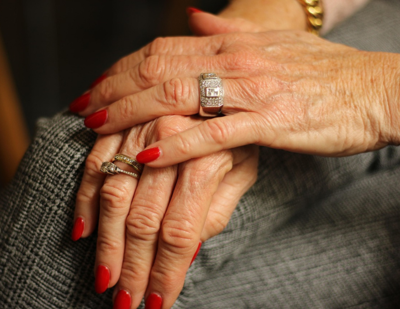 A diamond banded gold fashion ring on an older woman's hand.